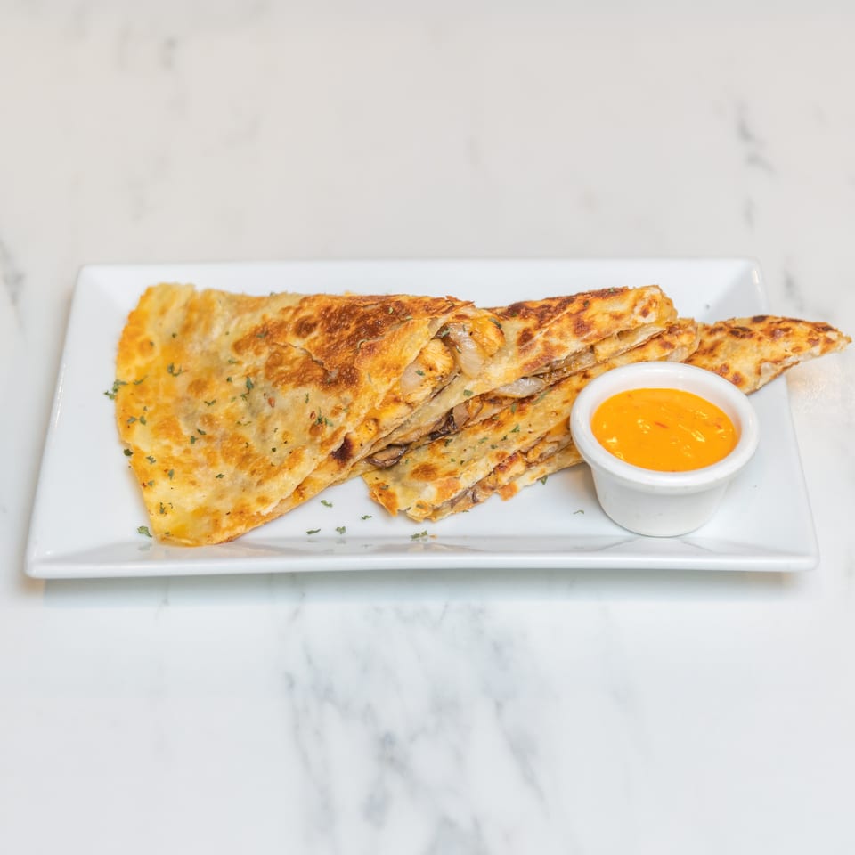 Golden-brown quesadillas filled with chicken, onions, and mushrooms, served with a side of orange dipping sauce.