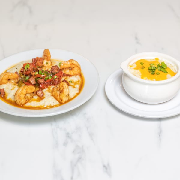 Shrimp and grits with bacon and peppers, alongside a bowl of cheesy grits with chives.