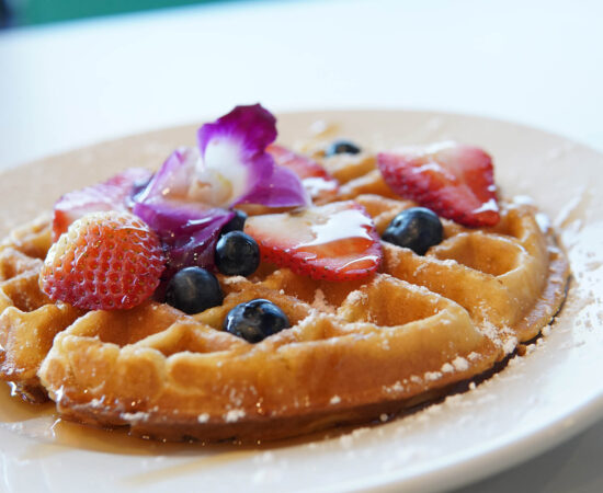 Waffle with fresh berries and syrup on a plate